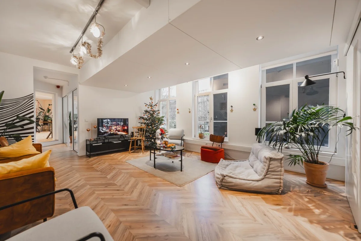 Modern ingerichte woonkamer aan de Korte Reguliersdwarsstraat met kerstboom, zithoek en houten visgraatvloer.